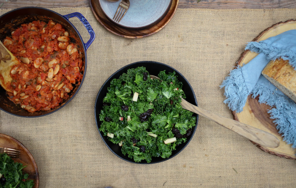 A flat lay of a table set with kale salad and various other foods