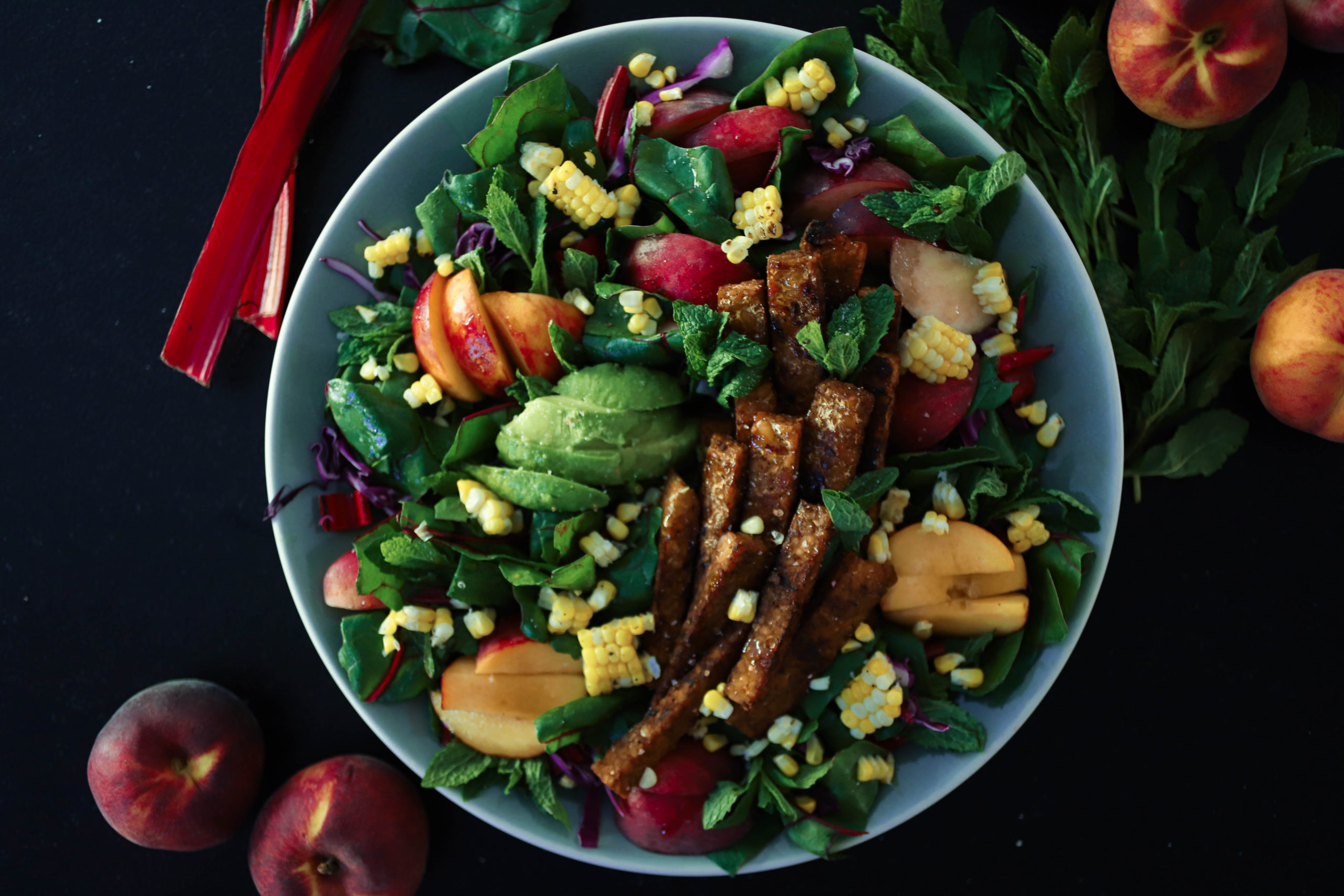 peach avocado tempeh salad on black backdrop