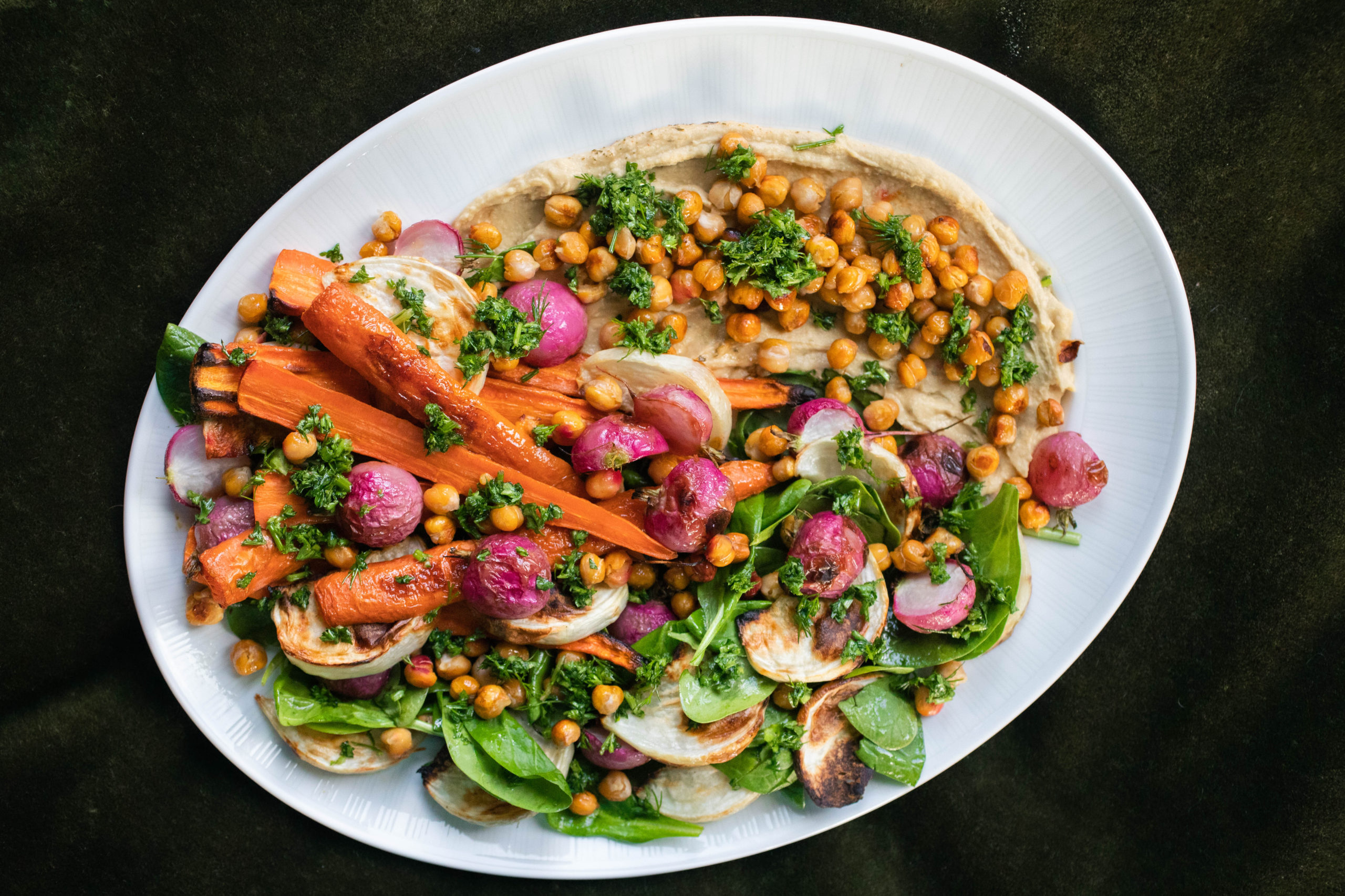 a spring salad of roasted carrots, radish, turnip, and chickpeas with spring greens, parsley sauce, and hummus