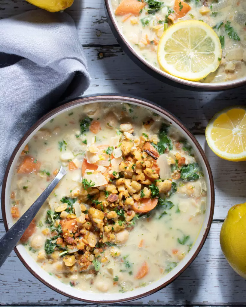 two bowls of lemon soup topped with tempeh crumble and fresh dill
