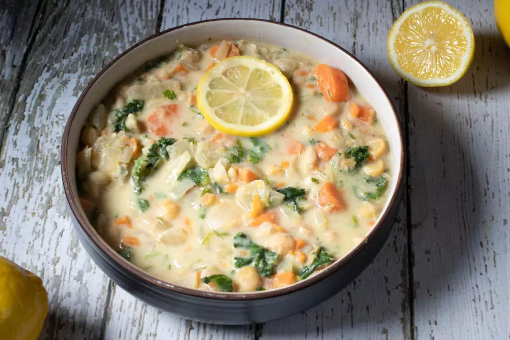 a bowl of lemon dill and chickpea soup on a wood table