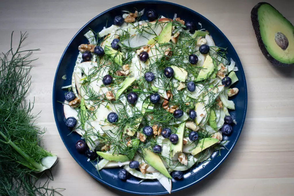 fennel salad with blueberries, avocado, and walnuts on a blue plate