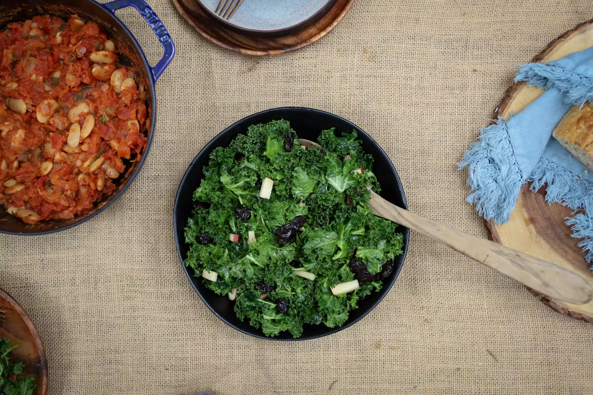 a table set with kale salad and various other foods